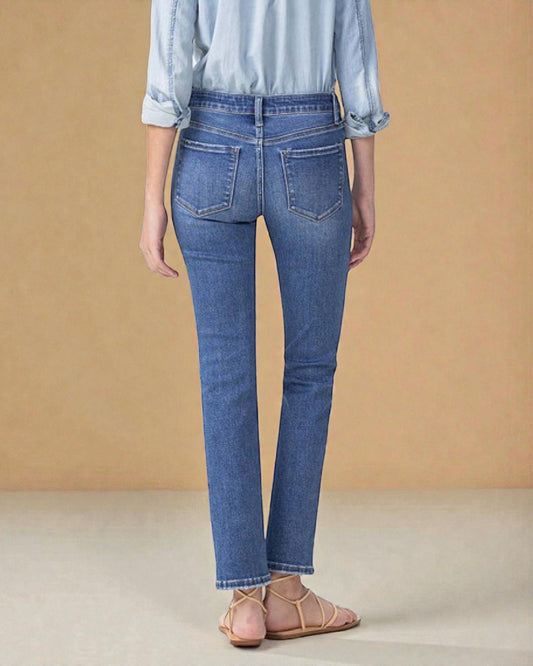 Person wearing blue jeans and a light blue shirt against a beige background