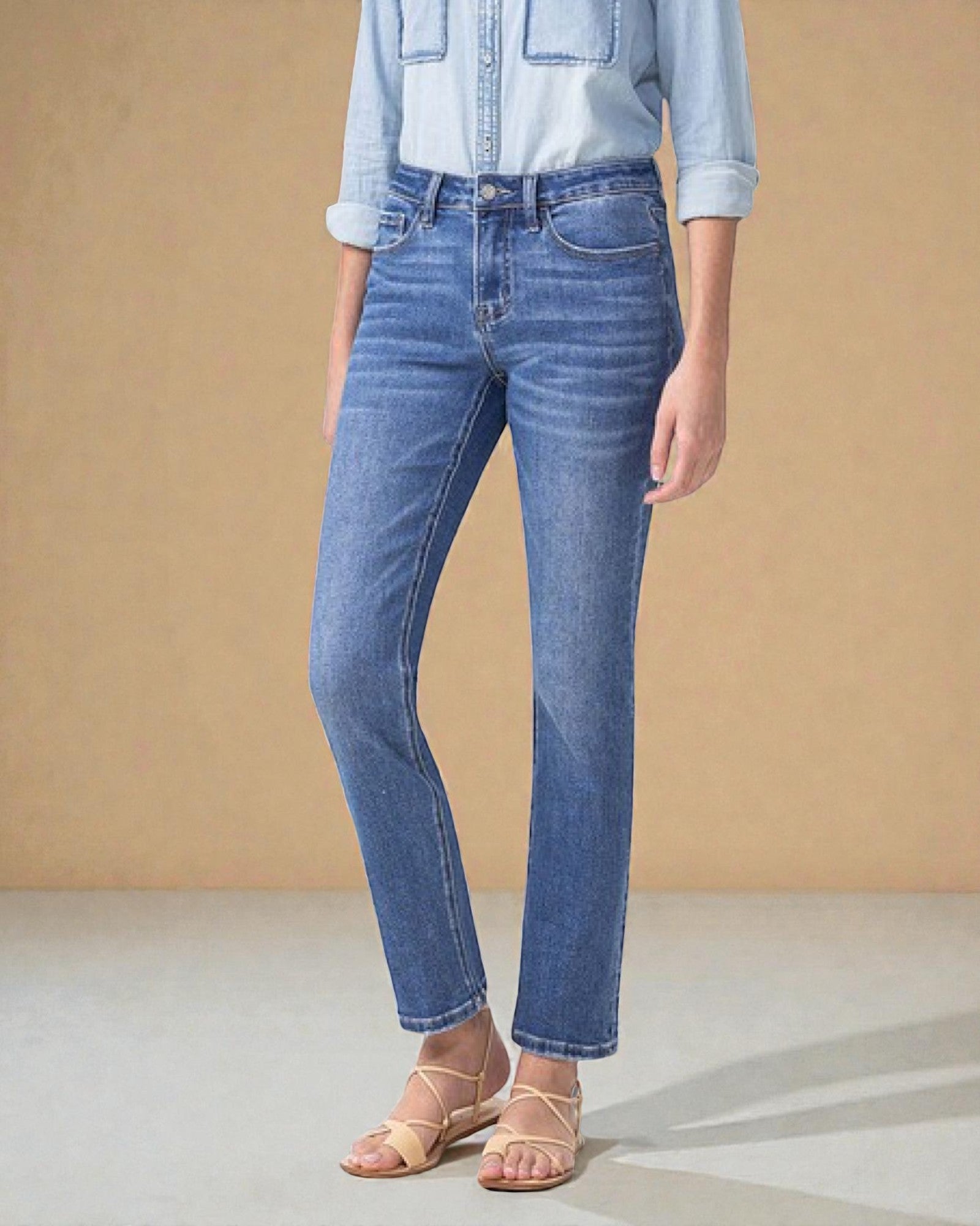 Person wearing blue jeans and a light blue denim jacket on a beige background