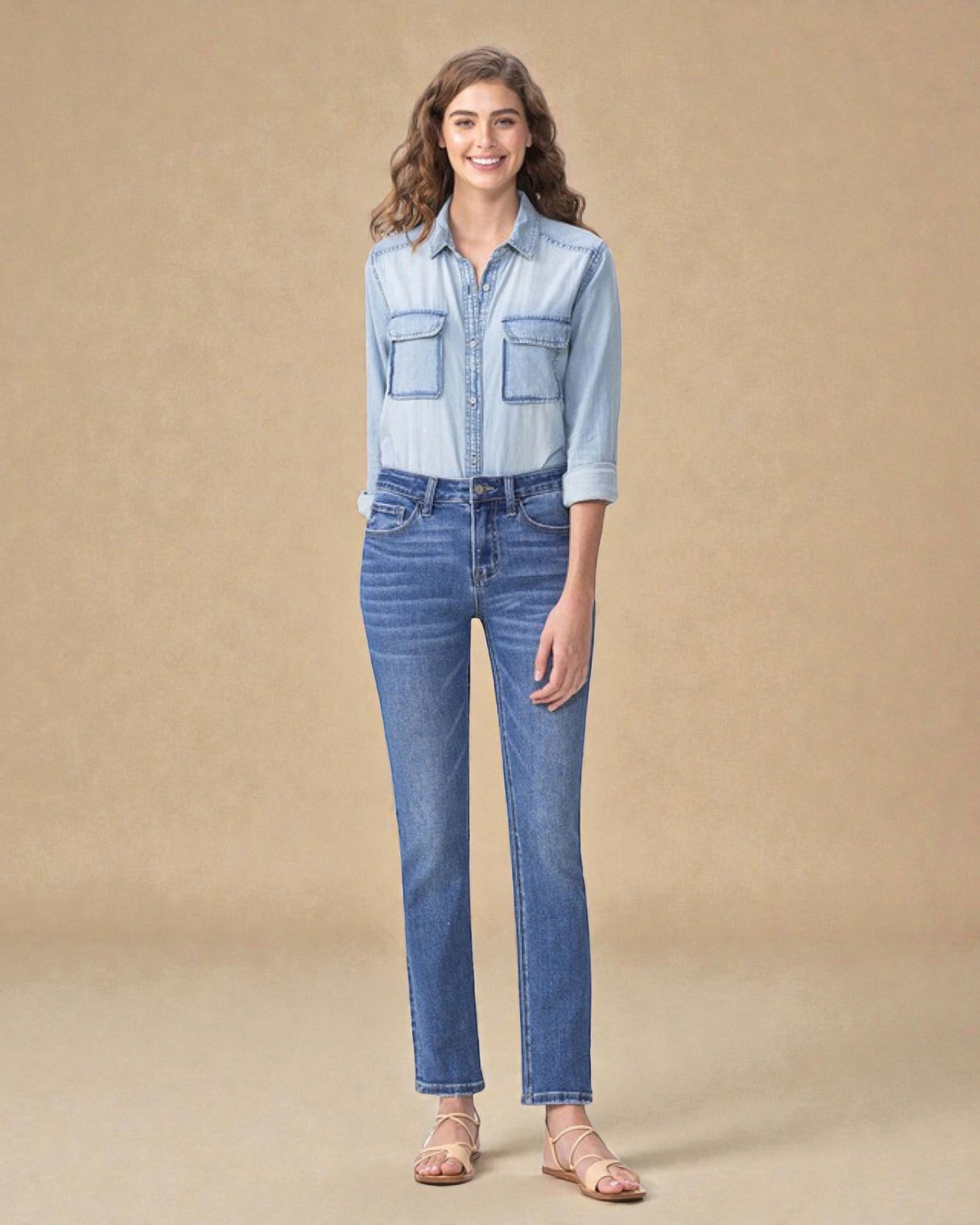 Woman wearing a light blue denim shirt and jeans on a beige background