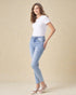 Woman wearing light blue jeans and a white t-shirt on a beige background