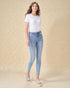 Woman wearing light blue jeans and a white t-shirt against a beige background
