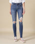 Person wearing distressed blue jeans on a beige background