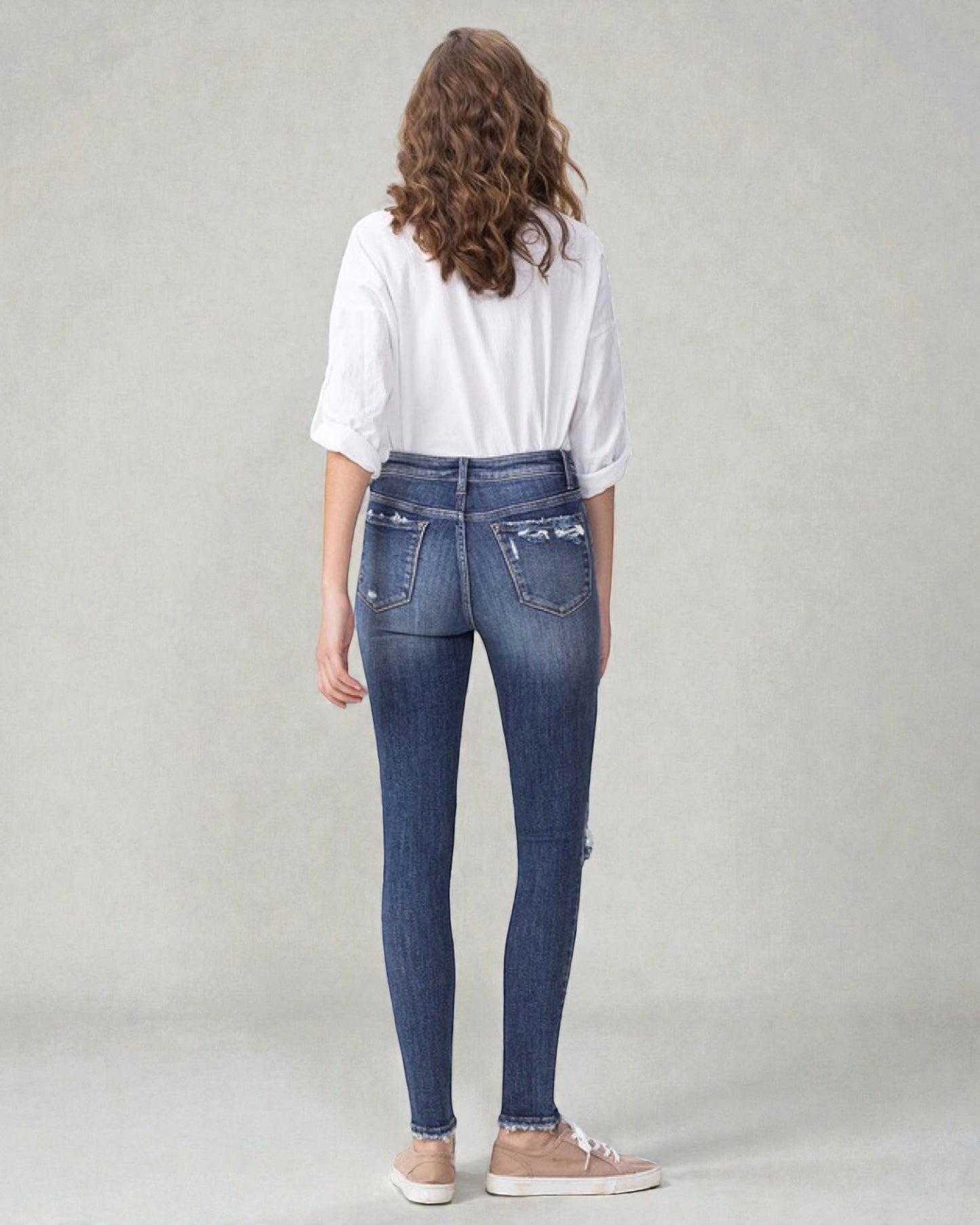 Person wearing blue jeans and a white shirt on a plain background