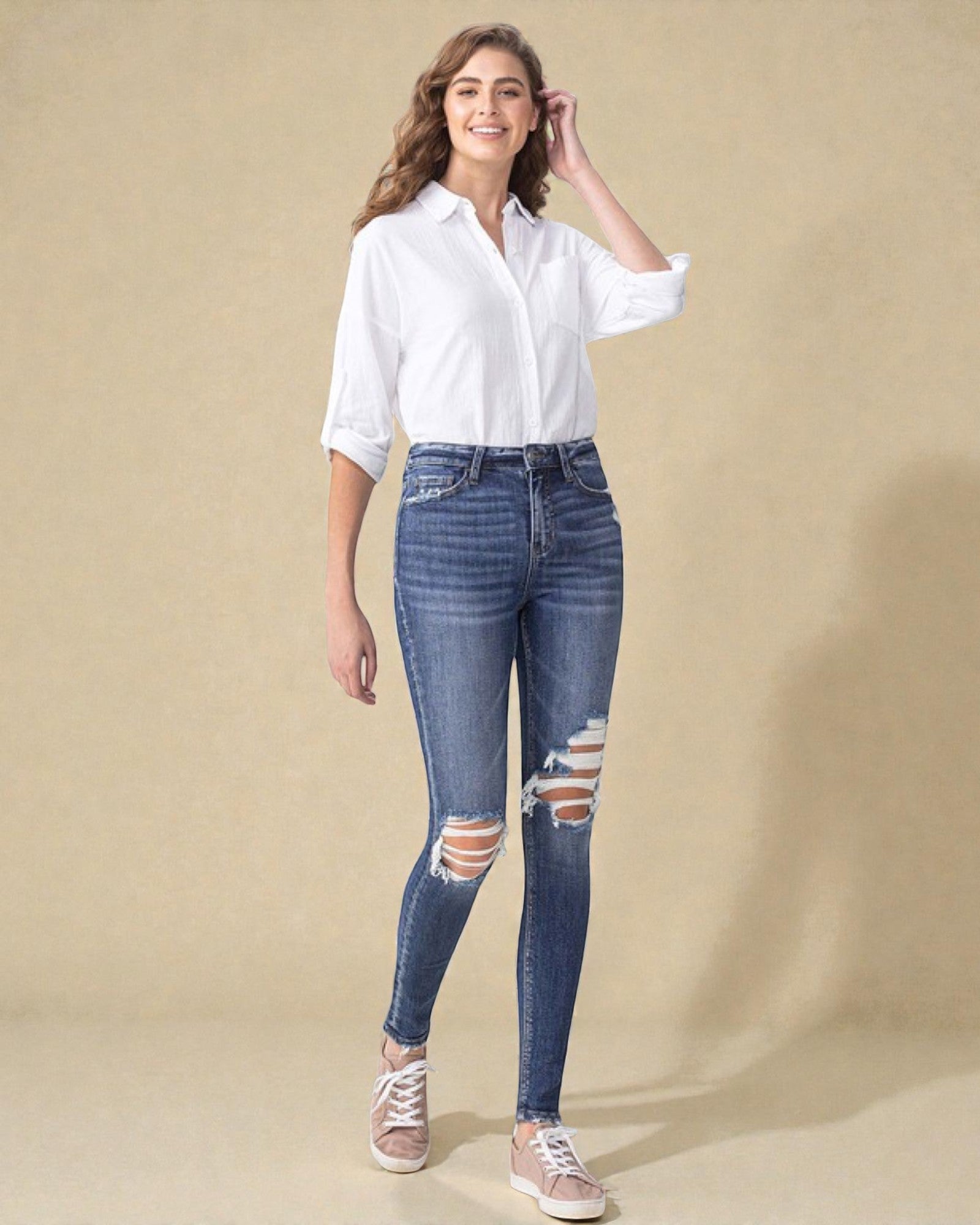 Woman wearing a white shirt and blue jeans with a beige background