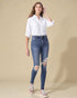 Woman wearing a white shirt and blue jeans with a beige background