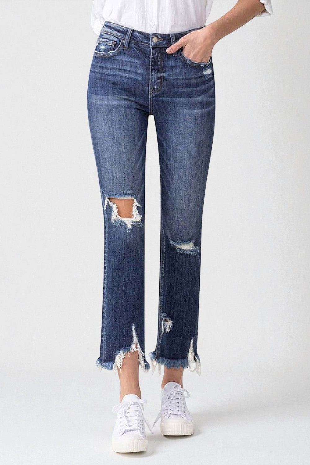 Person wearing distressed blue jeans and white sneakers on a white background