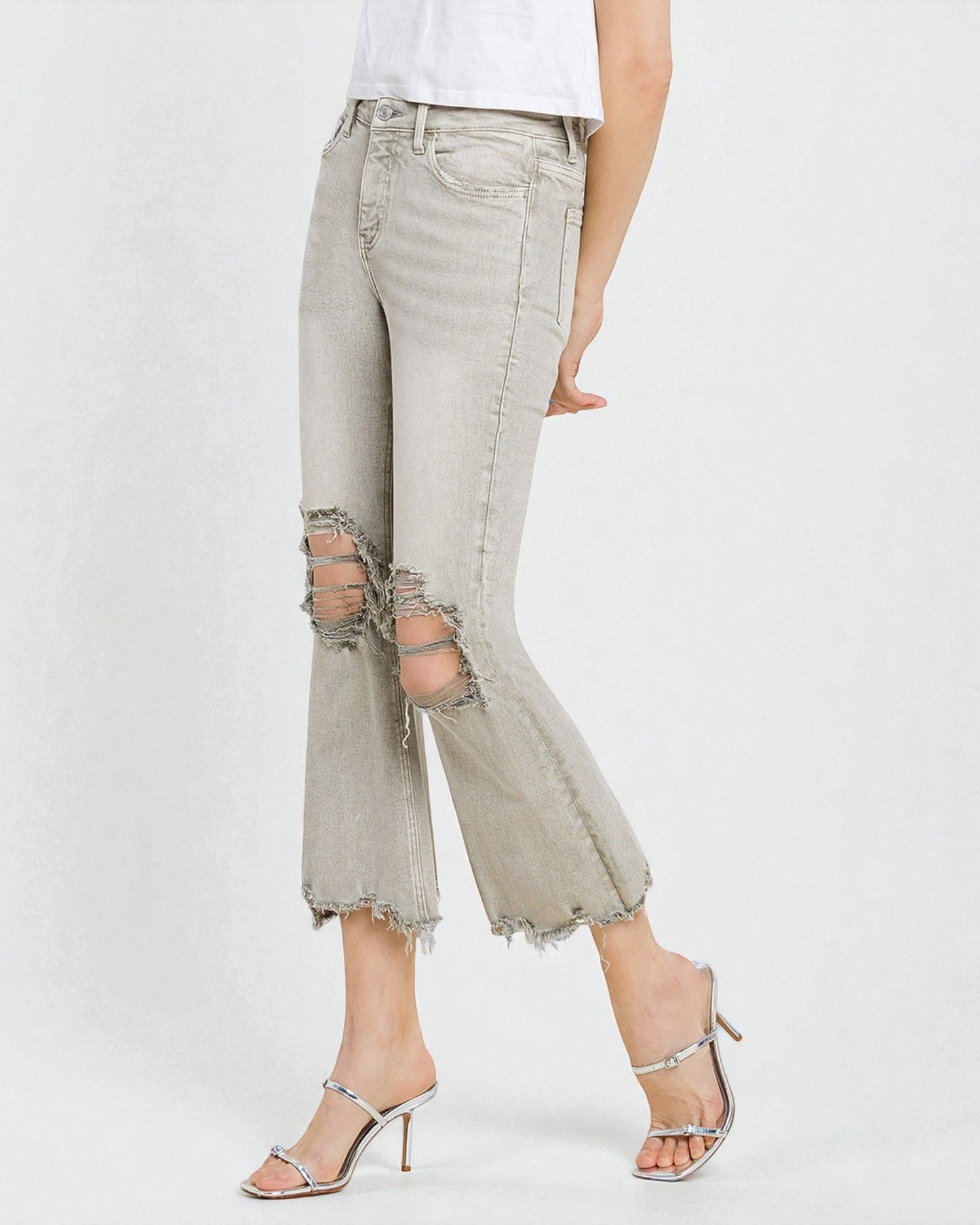 Light gray distressed jeans worn by a person on a white background