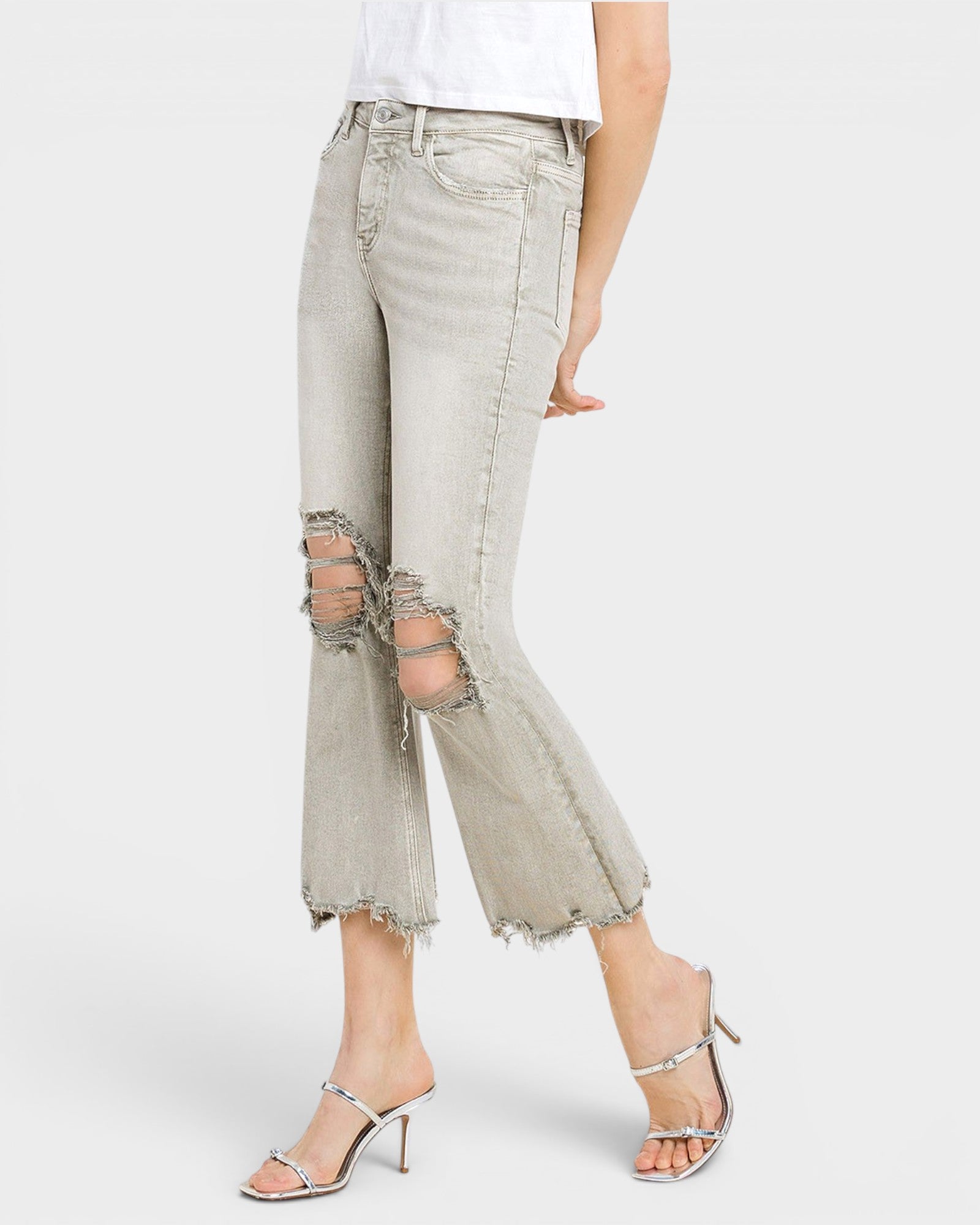 Light gray distressed jeans worn by a person on a white background