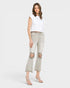 Woman wearing light gray distressed jeans and a white top on a white background