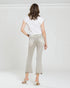 Woman wearing light-colored jeans and a white top on a plain background