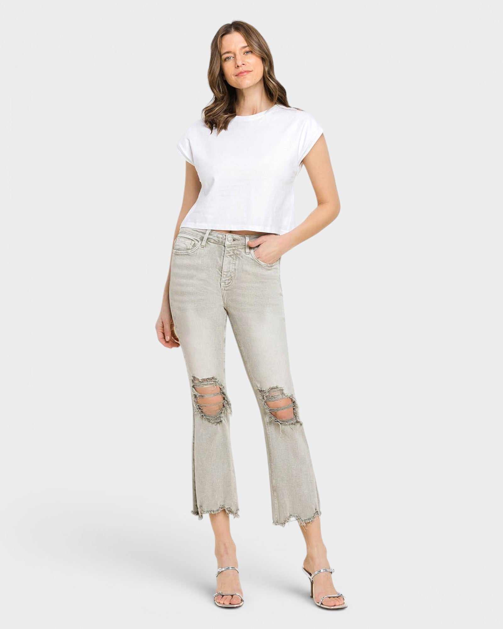 Woman wearing a white t-shirt and light gray distressed jeans on a white background