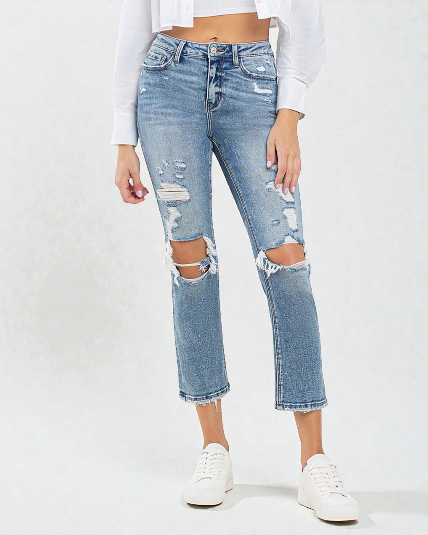 Person wearing light blue ripped jeans on a white background