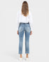 A woman shown from the back wearing light-wash blue cropped jeans, a white long-sleeve shirt, and white sneakers against a light gray studio background.