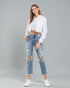 Woman wearing a white blouse and distressed jeans on a gray background