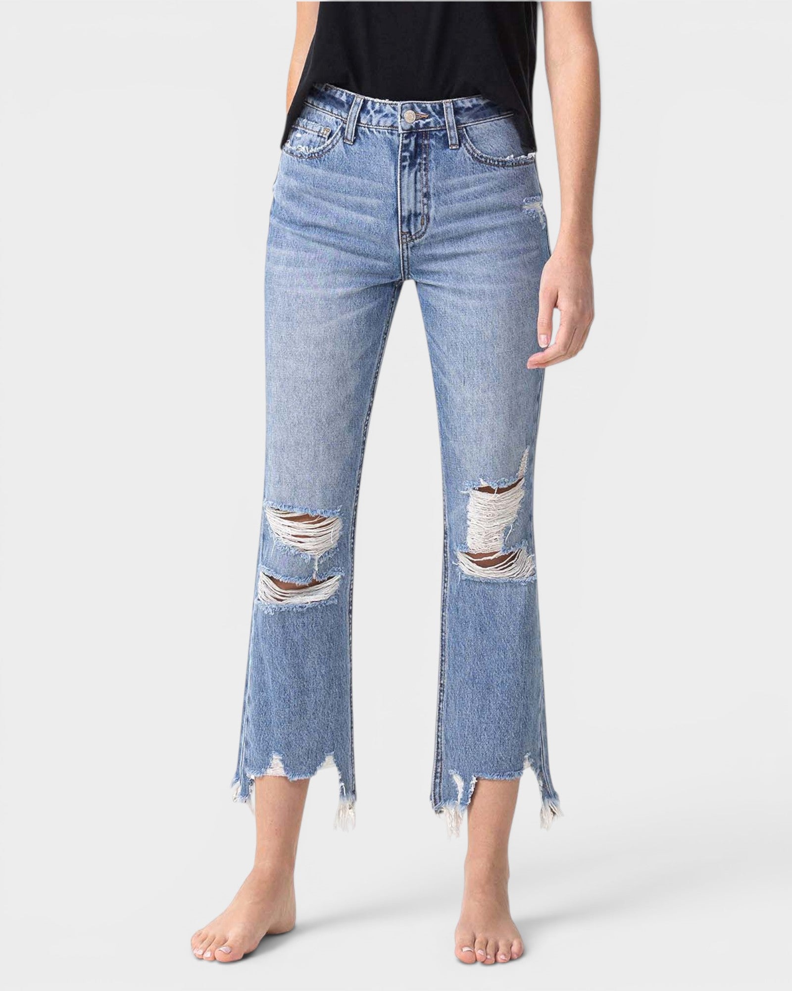 Person wearing distressed blue jeans on a white background