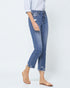 Person wearing blue jeans and beige sandals on a white background