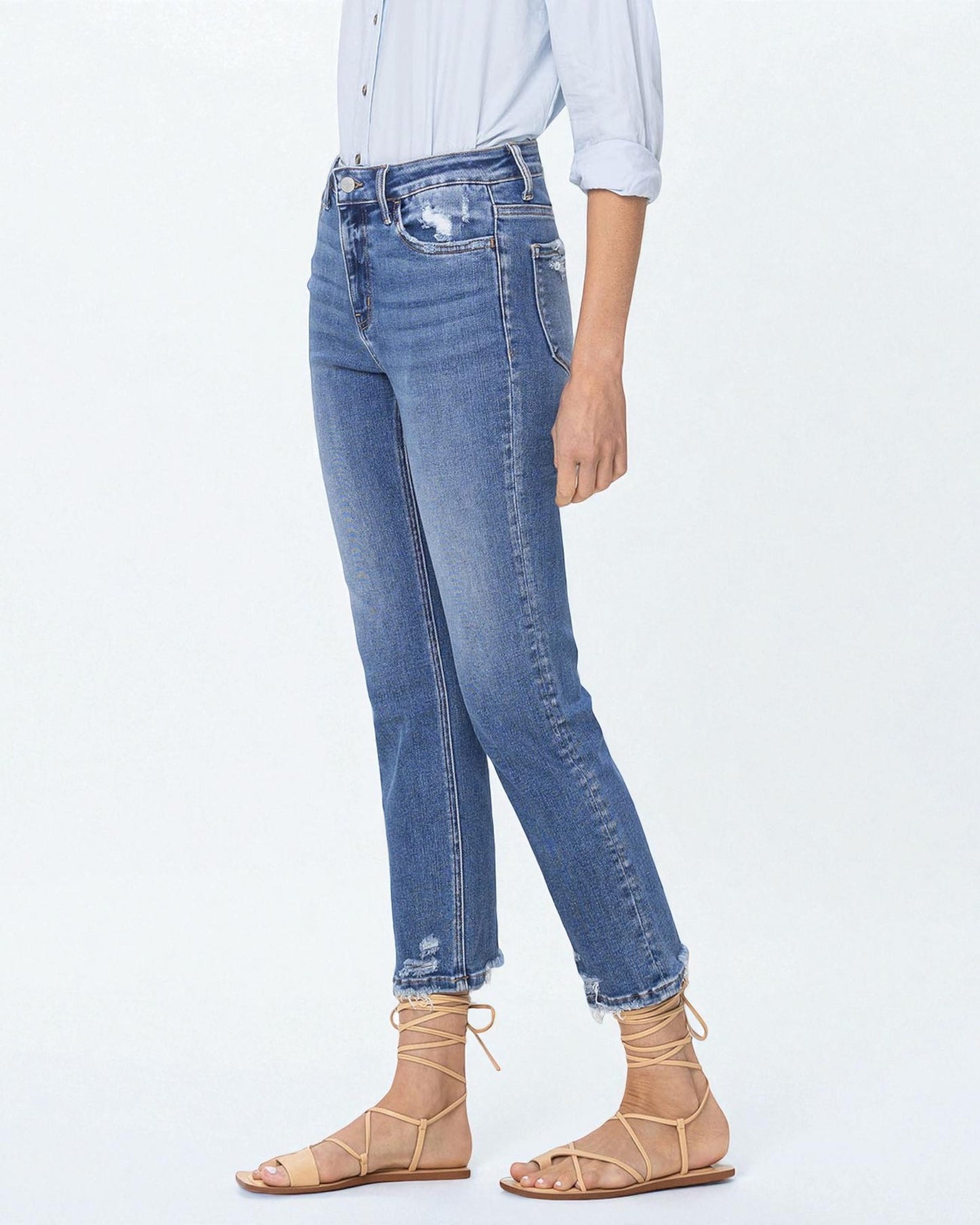 Person wearing blue jeans and beige sandals on a white background