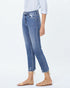 Person wearing blue jeans and beige sandals on a white background