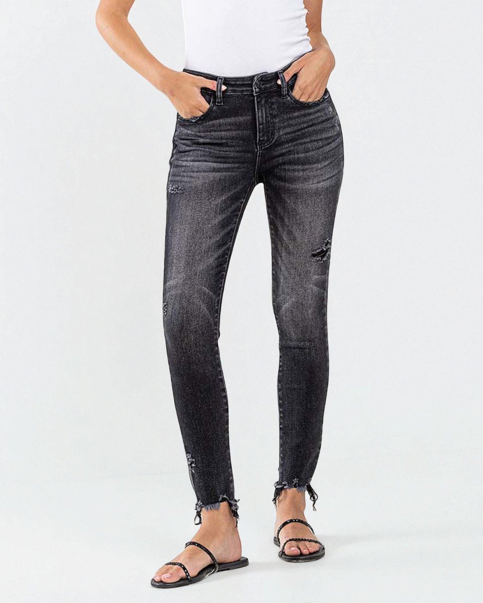 Person wearing black distressed jeans on a white background