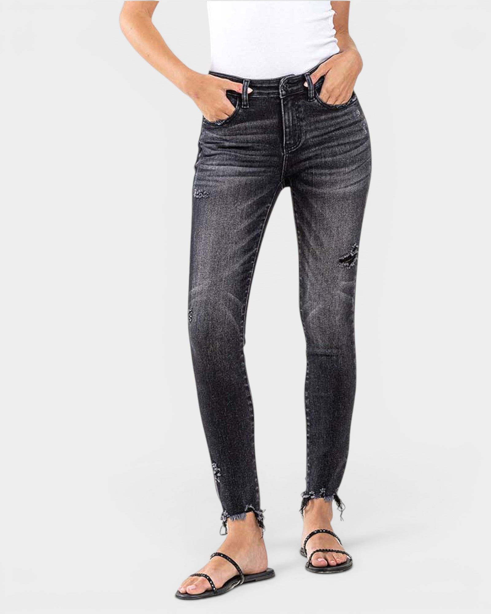 Person wearing black distressed jeans on a white background