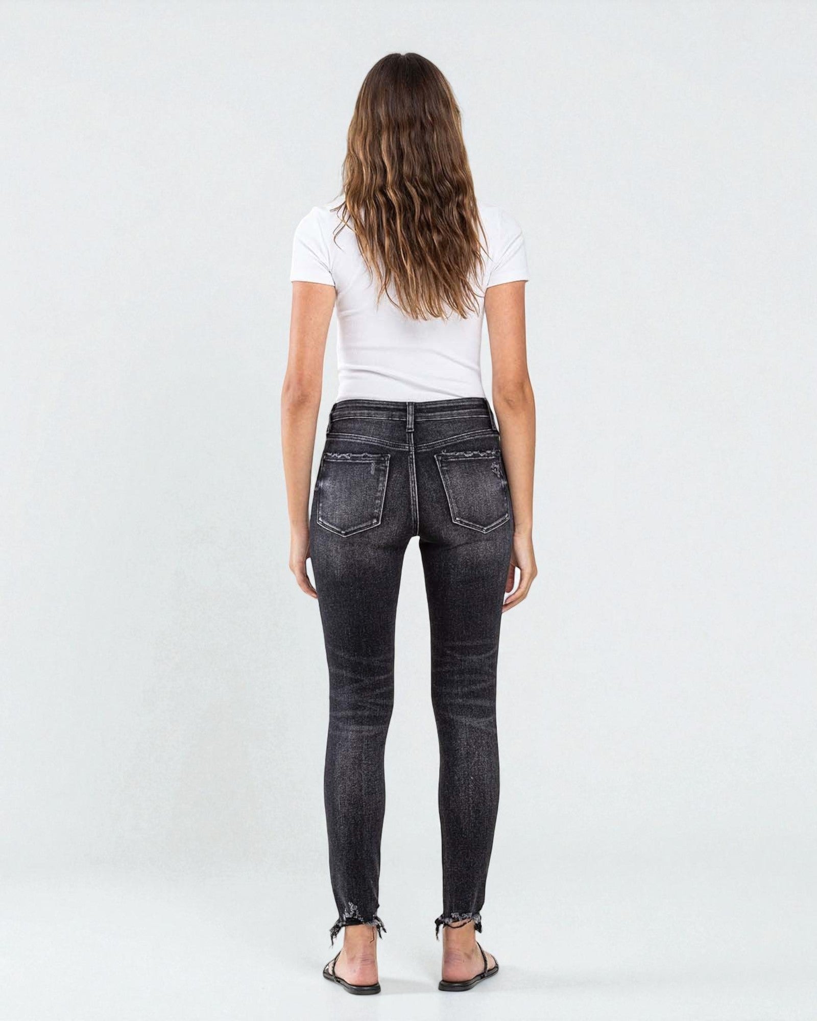 Person wearing black jeans and a white shirt on a white background