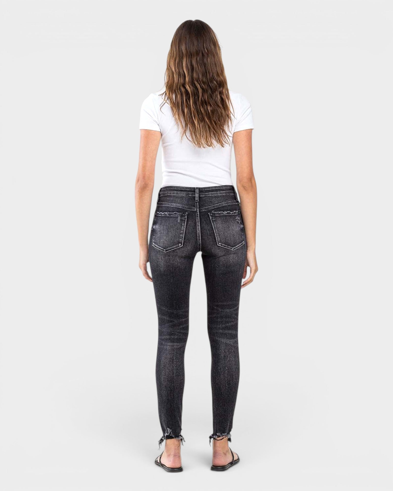 Person wearing black jeans and a white shirt on a white background