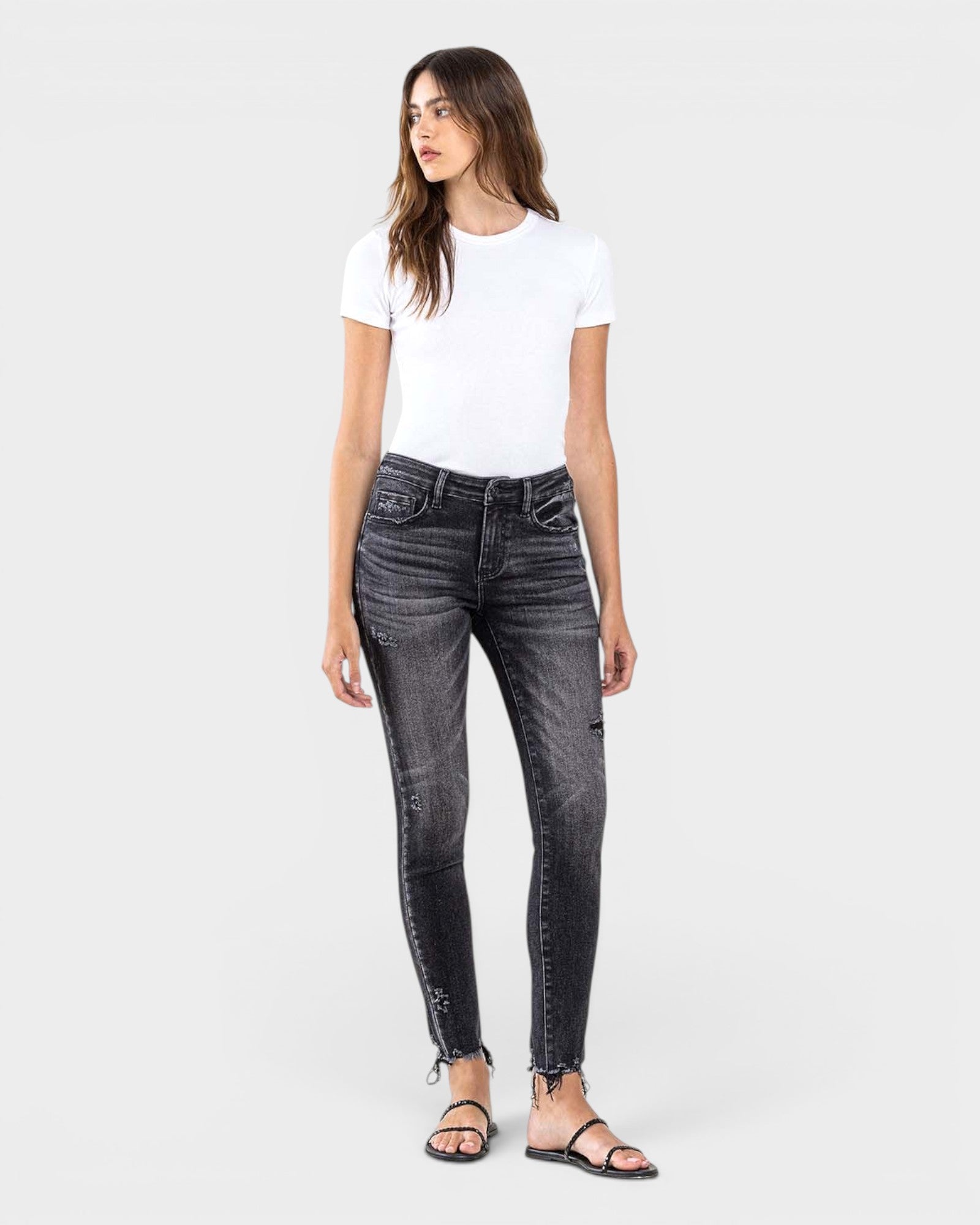 Woman wearing black jeans and a white t-shirt on a white background