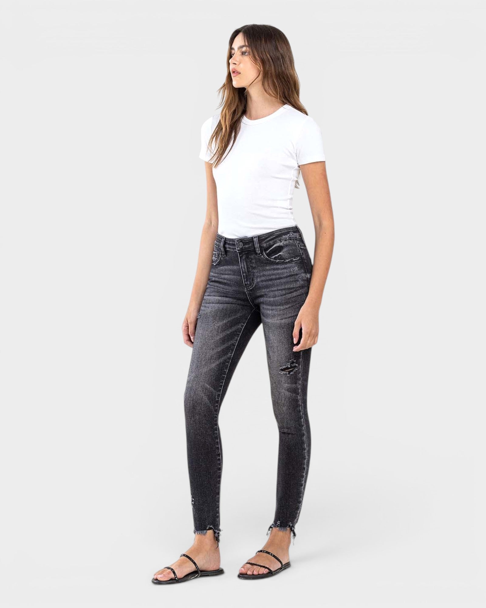 Woman wearing black distressed jeans and a white t-shirt on a white background
