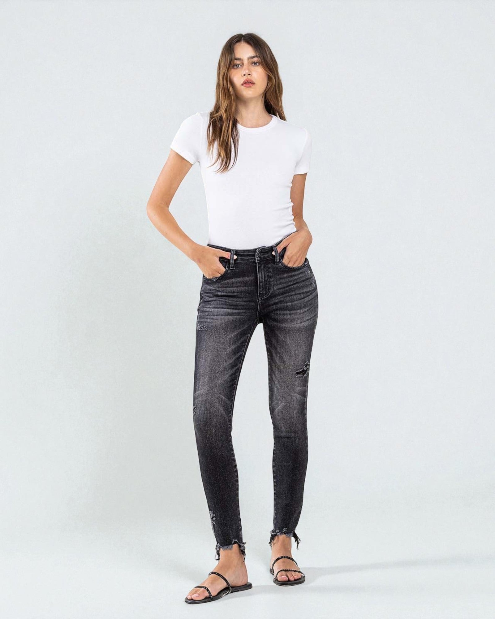 Woman wearing black jeans and a white t-shirt on a white background