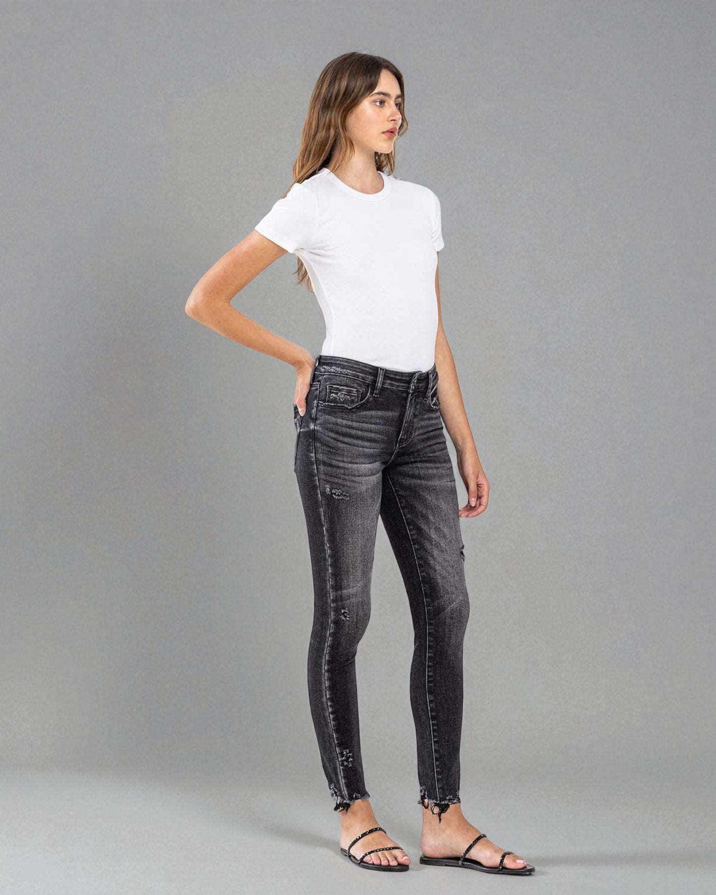 Woman wearing black jeans and a white t-shirt on a gray background