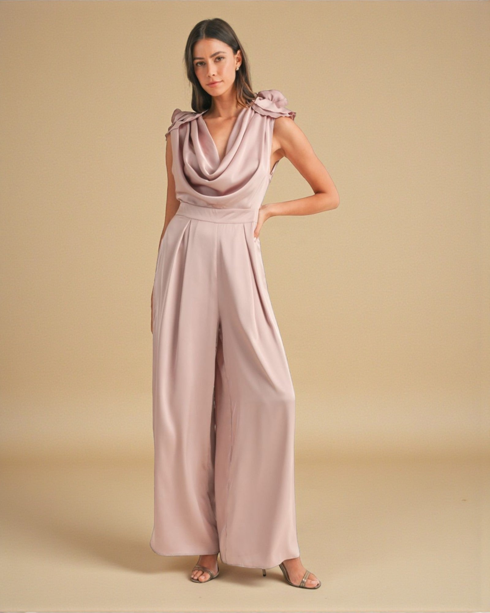 Woman wearing a pink jumpsuit against a beige background