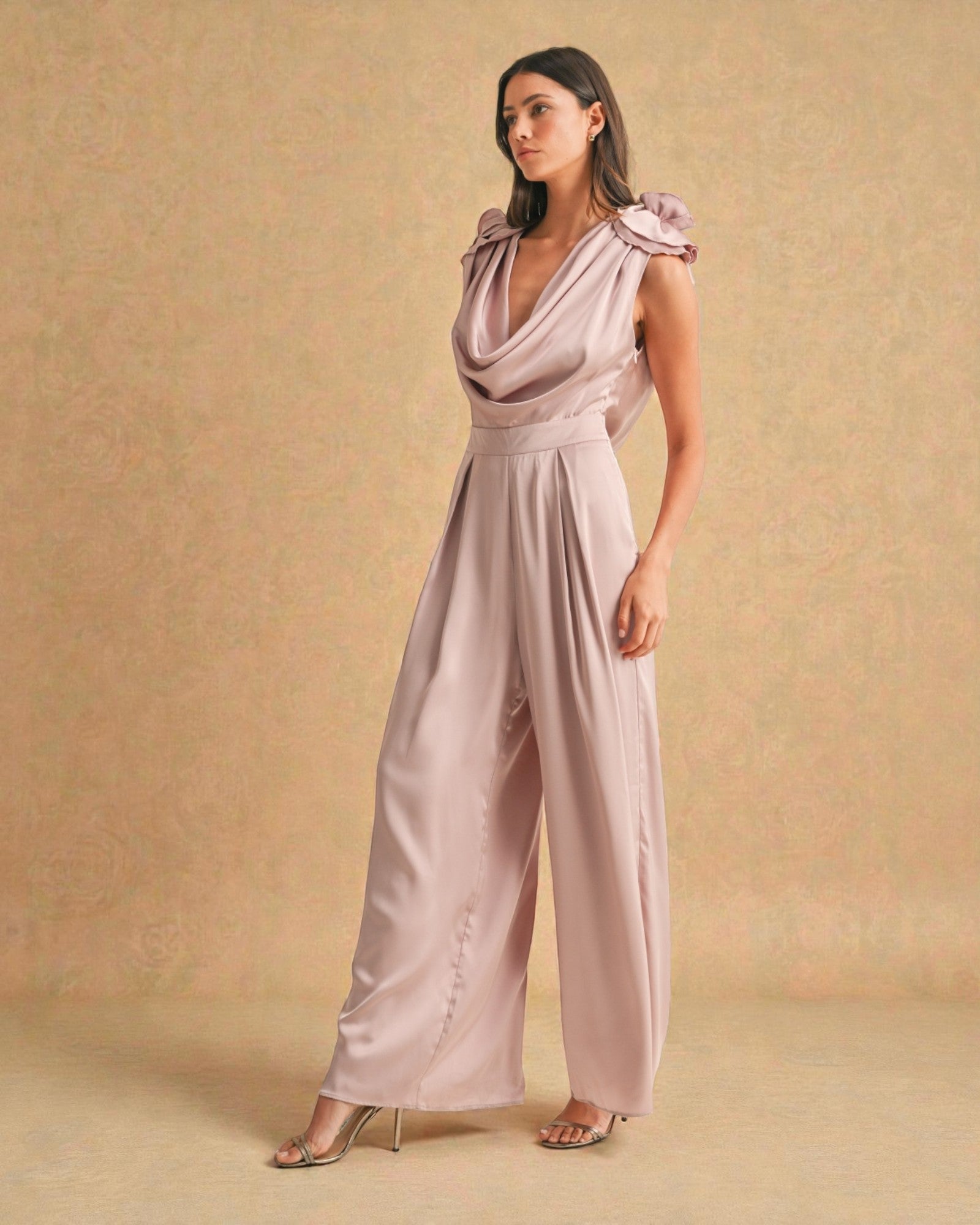 Woman wearing a light pink jumpsuit against a beige background