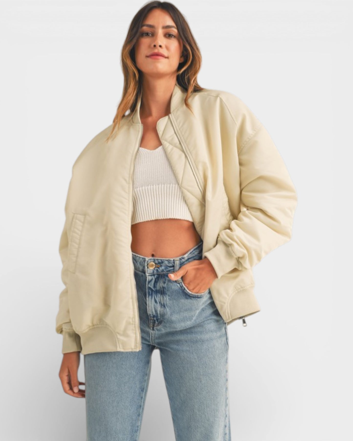 Woman wearing a beige jacket, white top, and blue jeans on a white background