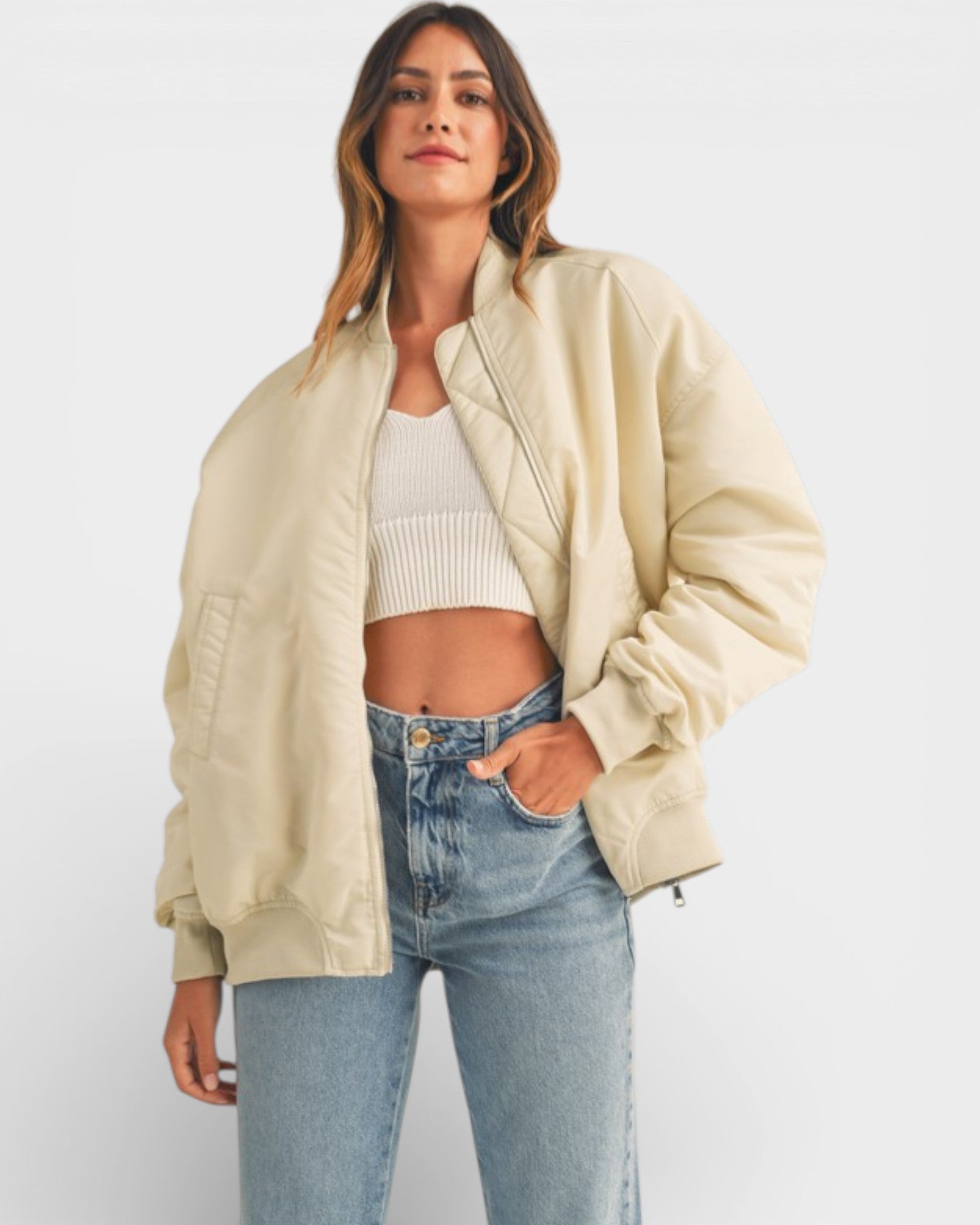 Woman wearing a beige jacket, white top, and blue jeans on a white background