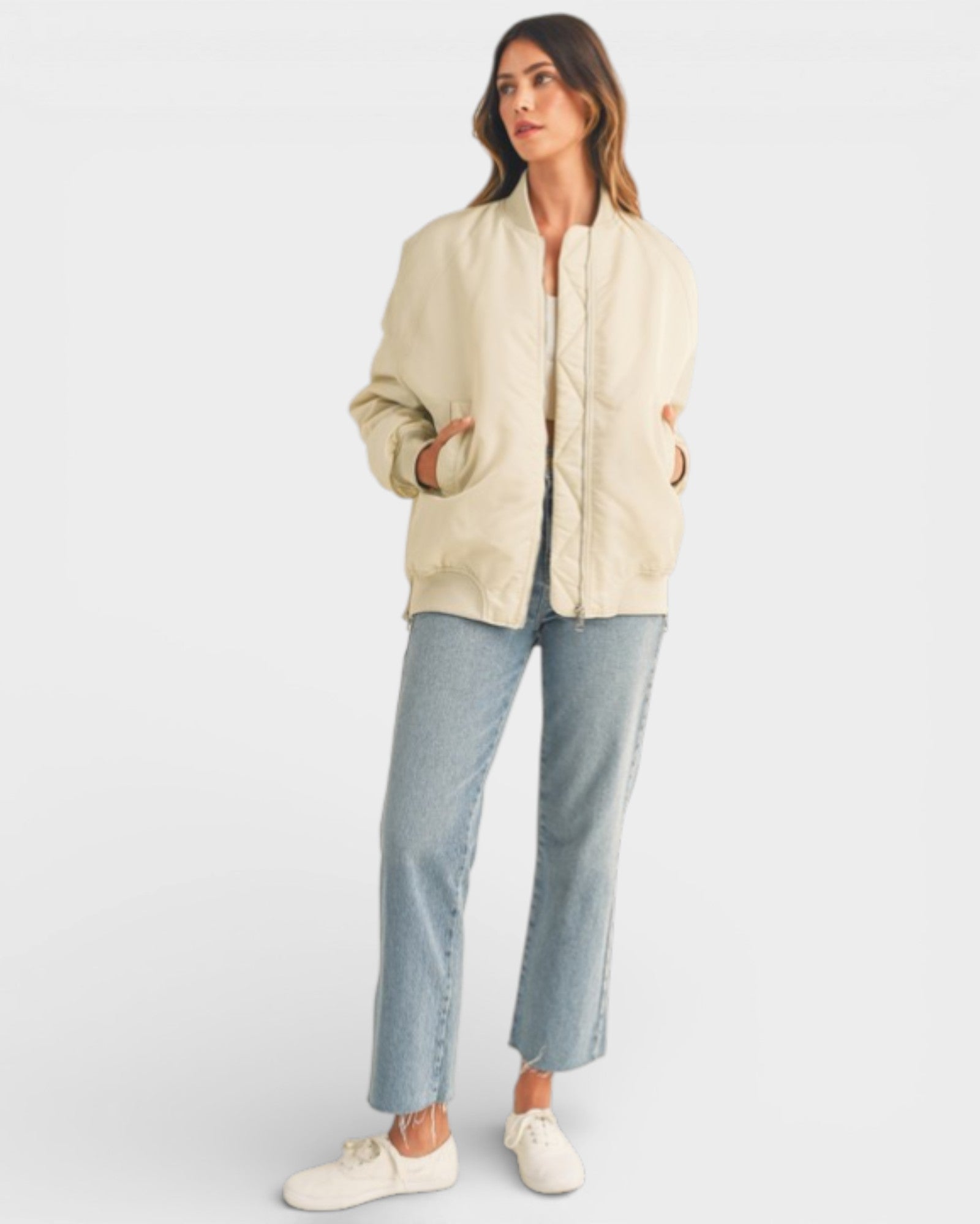 Woman wearing a beige jacket and light blue jeans on a white background