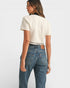 Woman wearing a white t-shirt and blue jeans on a plain background