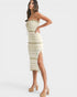 Woman wearing a strapless, off-white dress with a slit on a white background