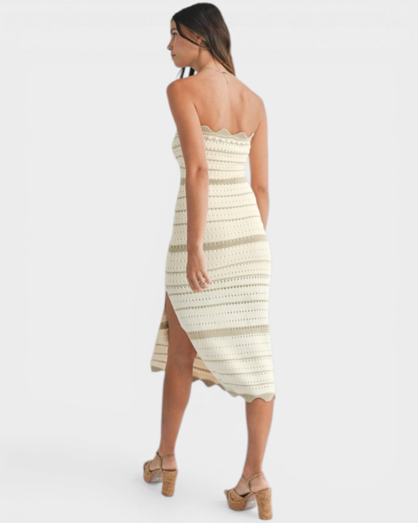 Woman wearing a strapless, off-white dress with a slit on a white background