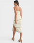Woman wearing a strapless, off-white dress with a slit on a white background