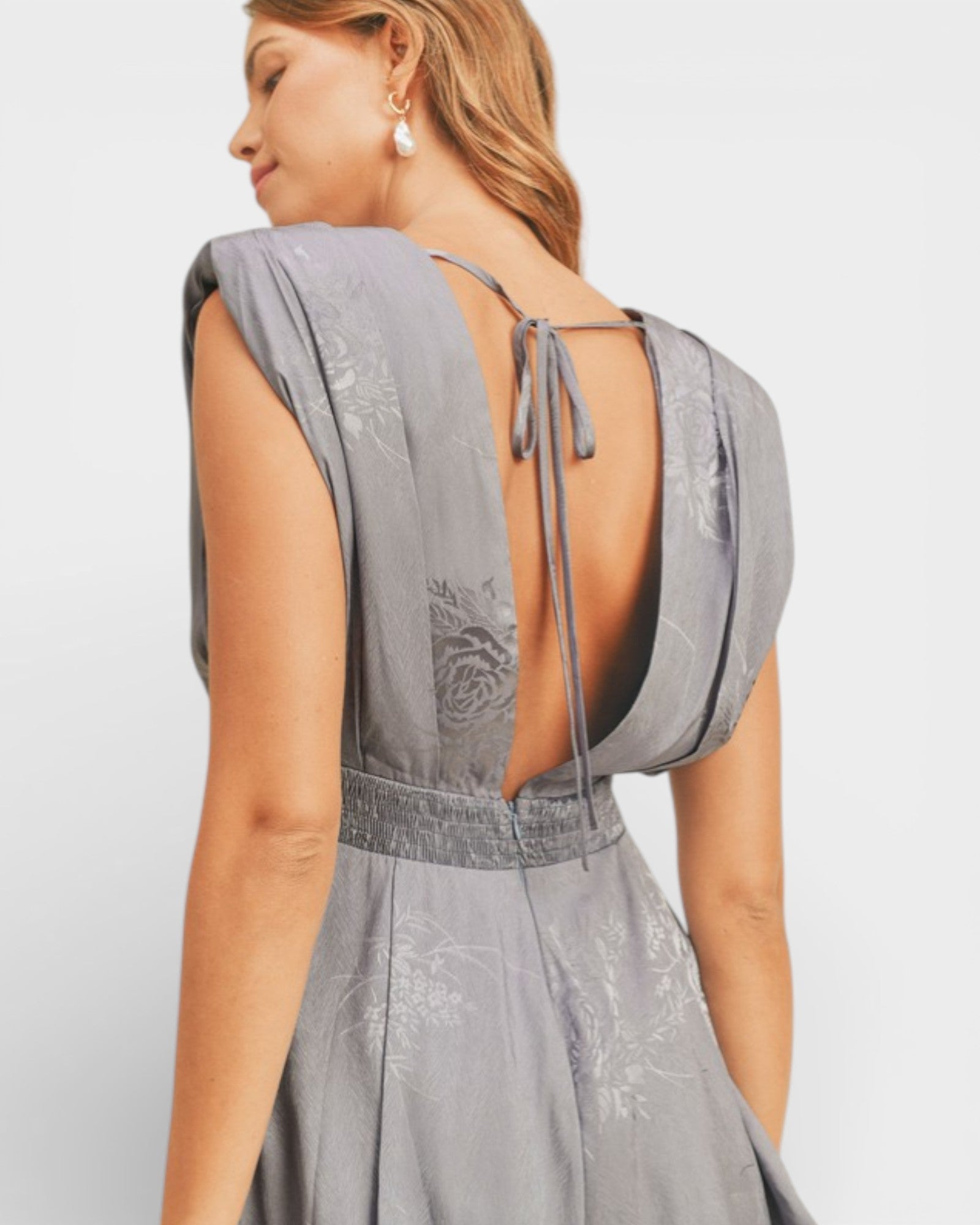Woman wearing a gray dress with an open back on a light gray background