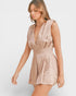 Woman wearing a beige romper against a white background