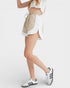 Person wearing a white and beige outfit with Adidas sneakers on a white background