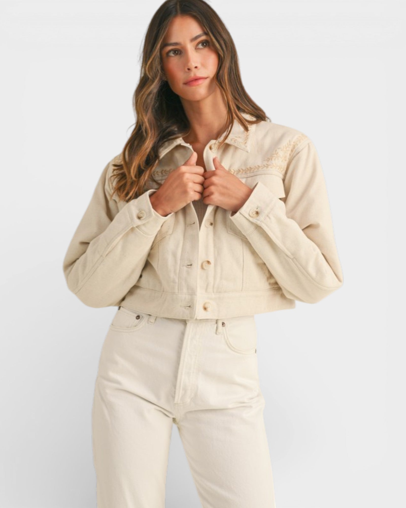 Woman wearing a beige denim jacket and pants on a white background