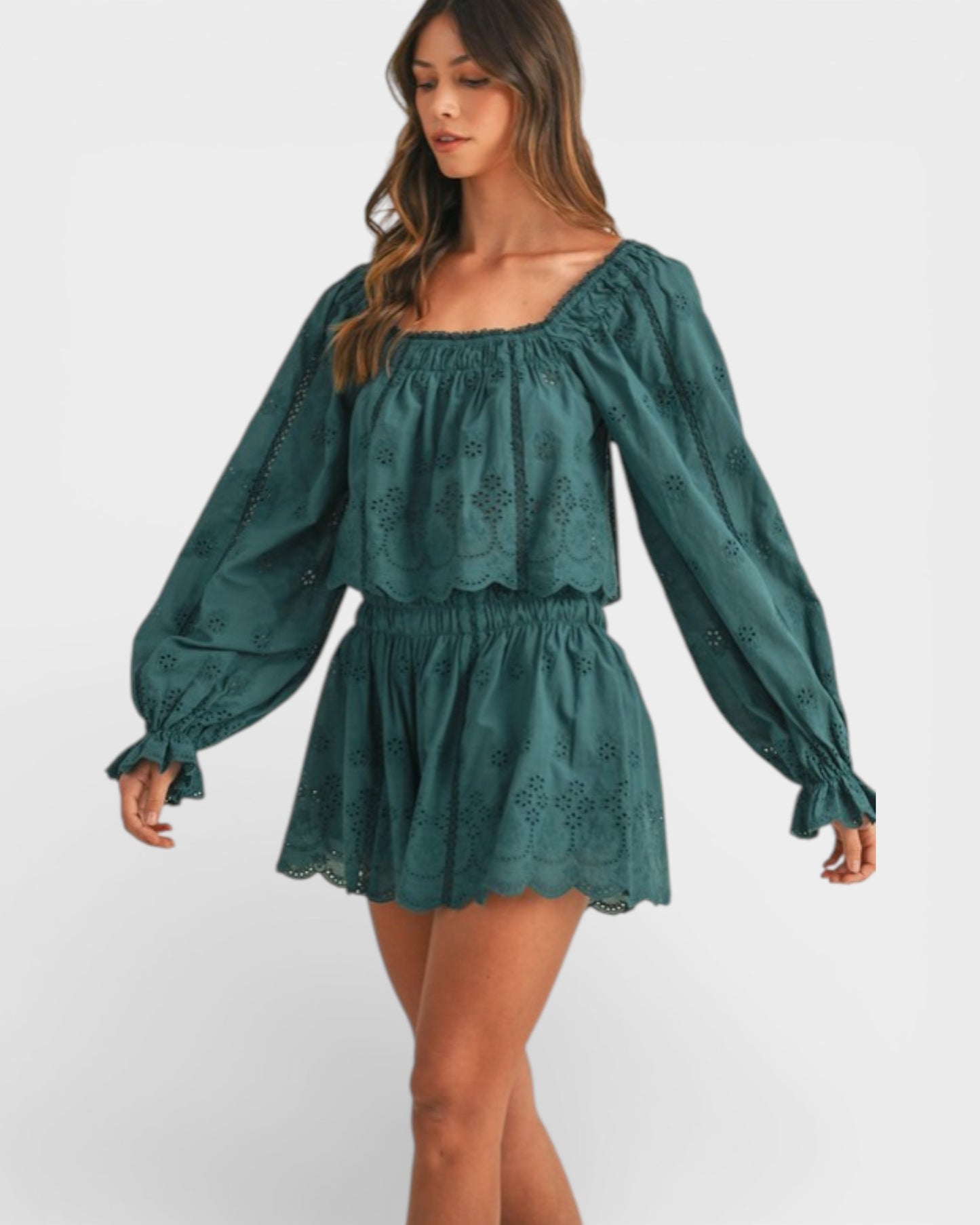 Woman wearing a green dress with long sleeves on a white background