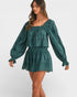 Woman wearing a green dress with long sleeves on a white background