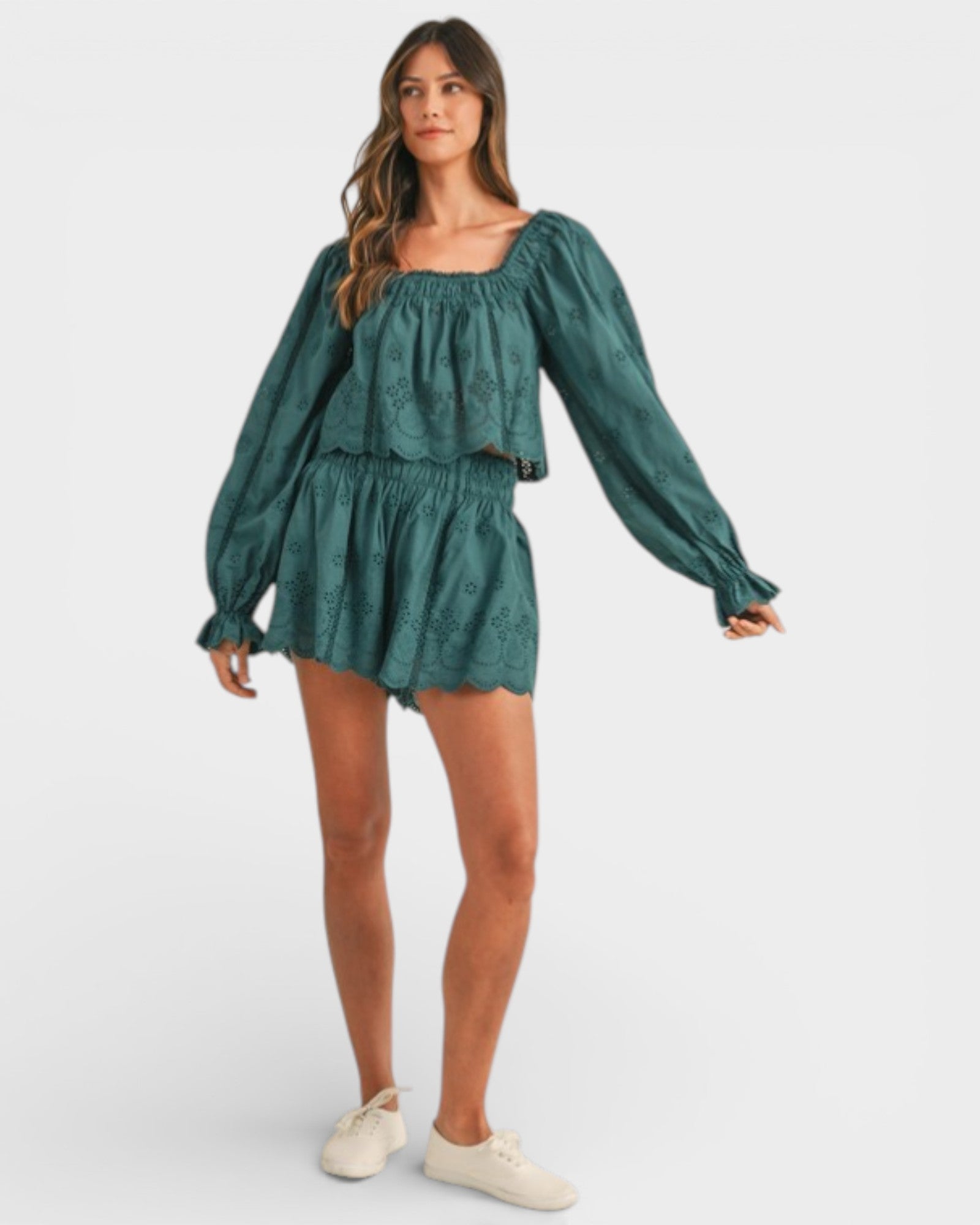 Woman wearing a green long-sleeve top and shorts set on a white background