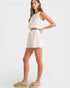 Woman wearing a white outfit with shorts and a top on a plain background