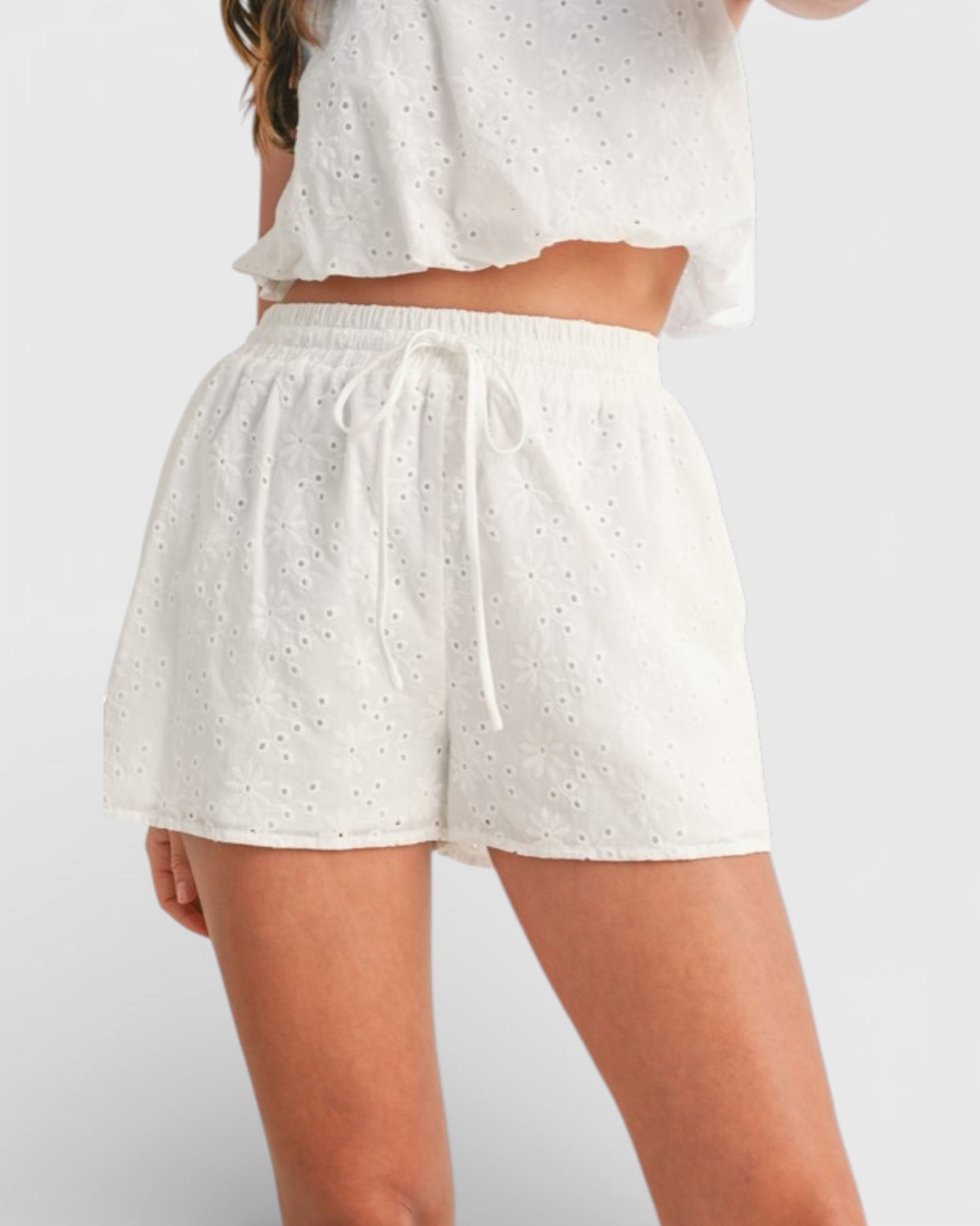 White shorts with a subtle pattern worn by a person on a plain background