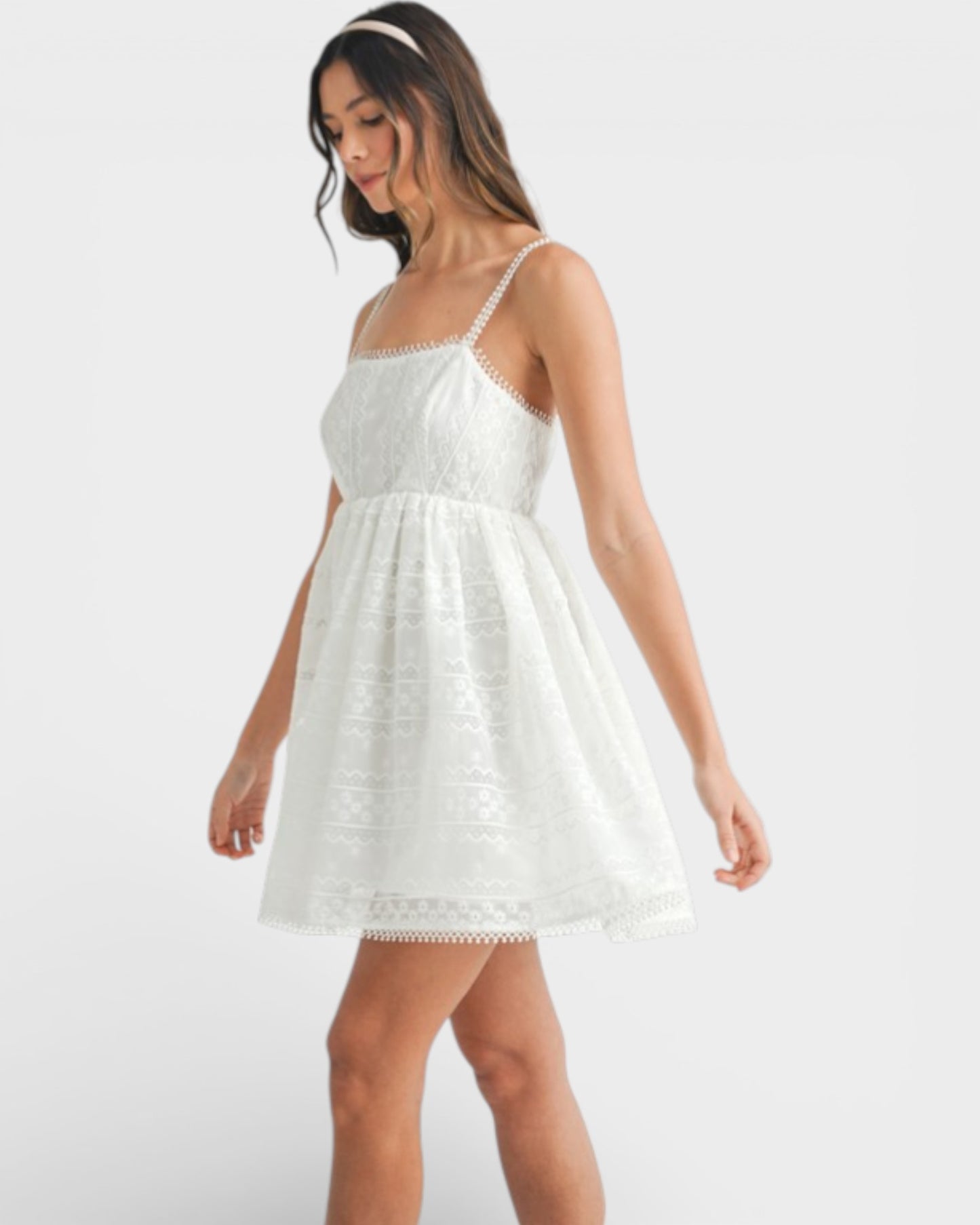 Woman wearing a white lace dress on a plain background