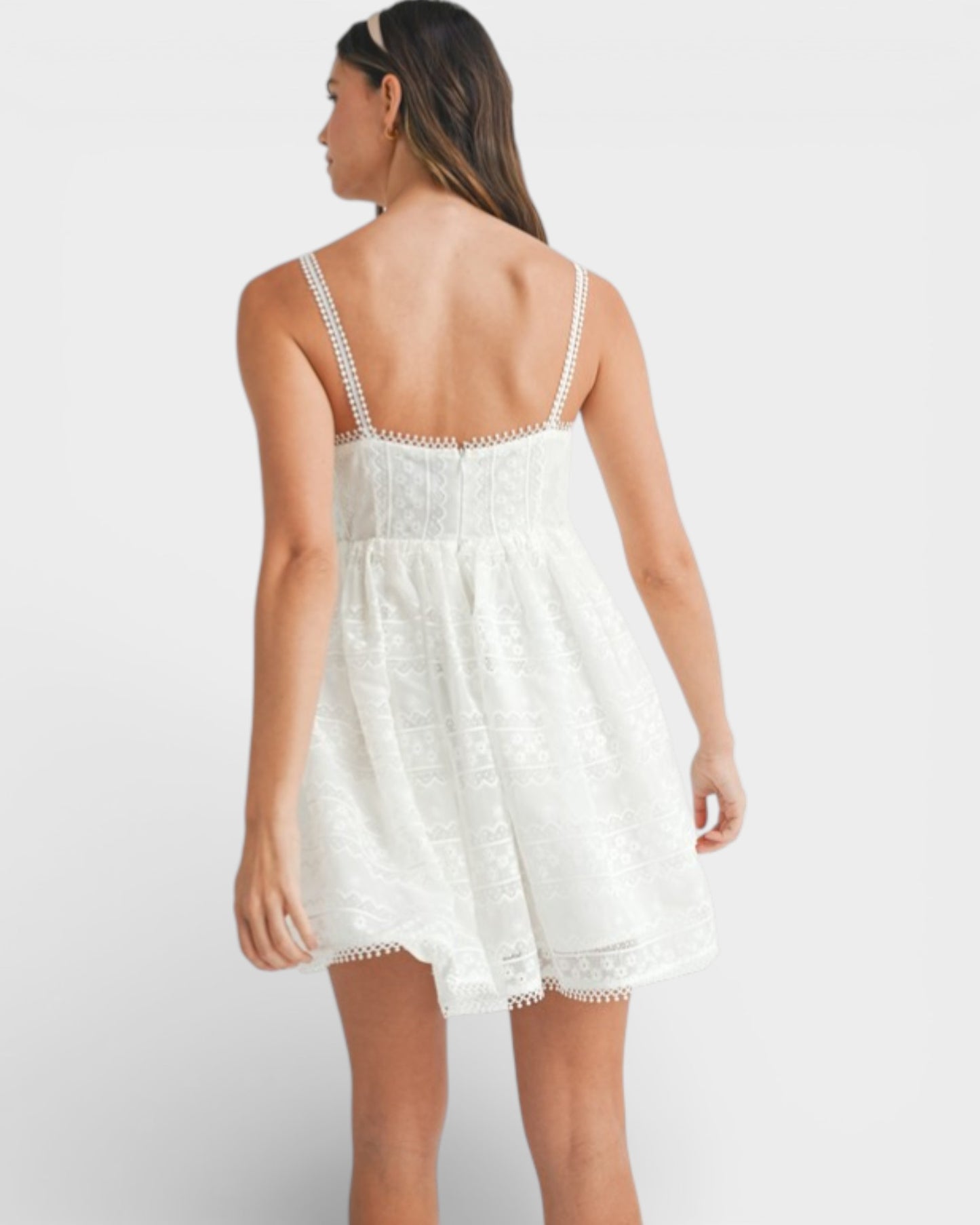 Woman wearing a white lace dress against a plain background